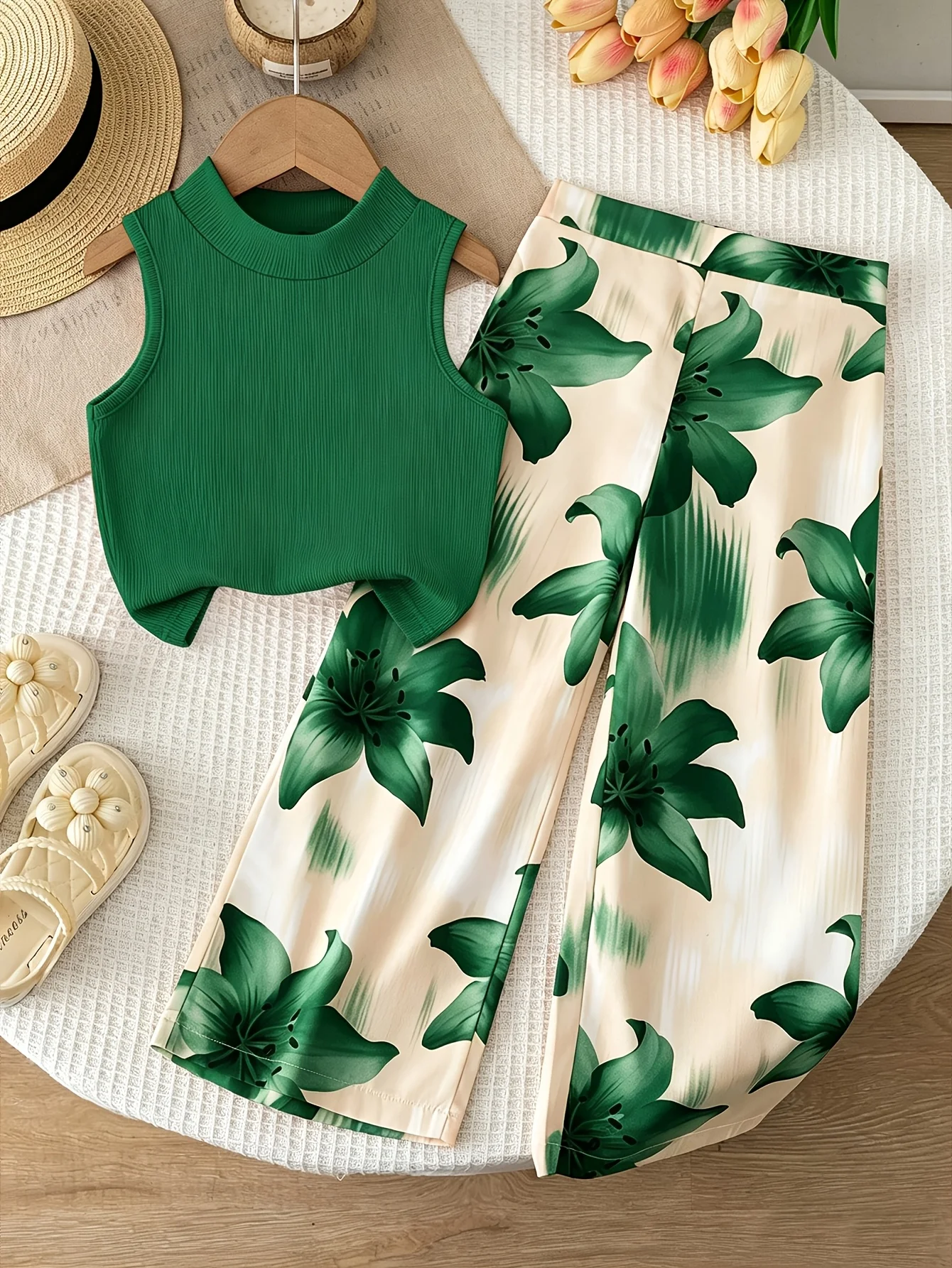 Conjunto de dos piezas estilo vacacional naranja para niñas: top corto sin mangas con cuello simulado, de color liso y textura acanalada, combinado con pantalón fluido con estampado de lirios.
