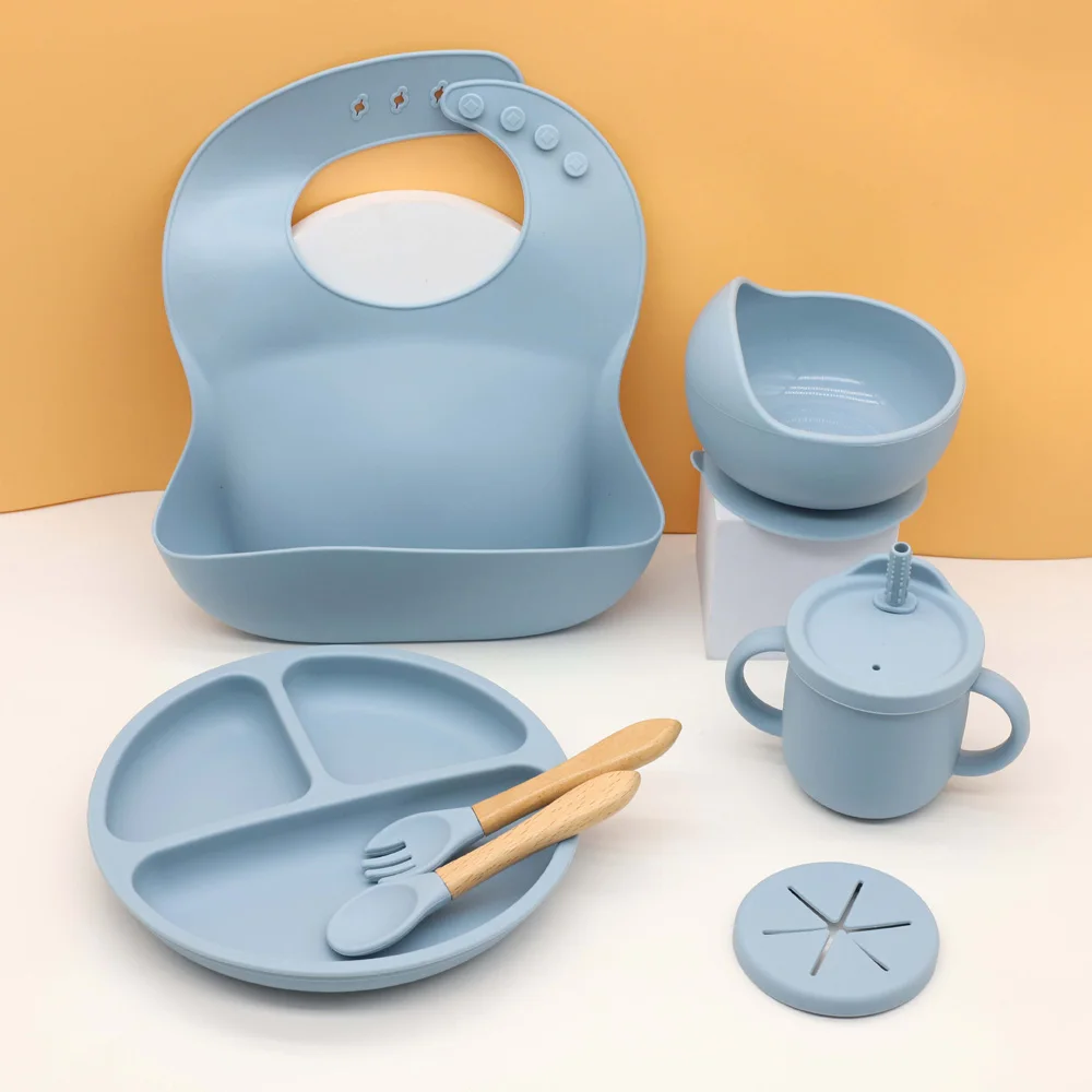 Juego de vajilla de silicona para bebé de 7 piezas, babero, plato, tazón con ventosa, vaso 2 en 1, taza para refrigerios, cuchara y tenedor de madera