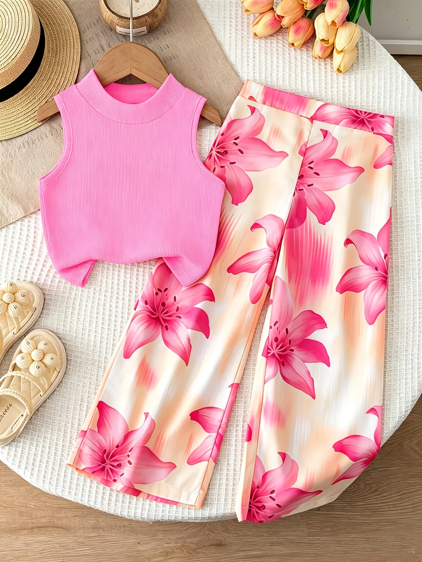 Conjunto de dos piezas estilo vacacional naranja para niñas: top corto sin mangas con cuello simulado, de color liso y textura acanalada, combinado con pantalón fluido con estampado de lirios.